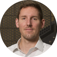 Headshot of David Hoelzle wearing a light shirt, against an indoor patterned background.