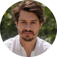 Headshot of Andrej Risteski with short hair and facial hair, wearing a light shirt, photographed outdoors.