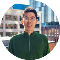 Headshot of Jie Ding wearing glasses and a green sweater, smiling outdoors.