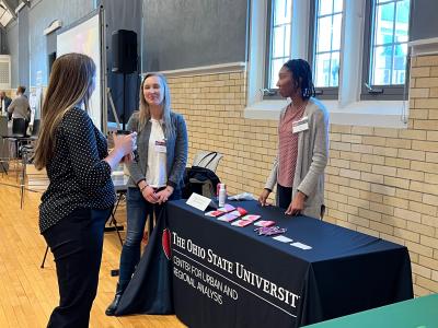 A staff member, student and visitor talking at the CURA table display