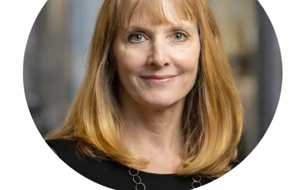Headshot of Dr. Missy Cummings, with shoulder-length blonde hair, wearing a black top and necklace, against a softly blurred background.
