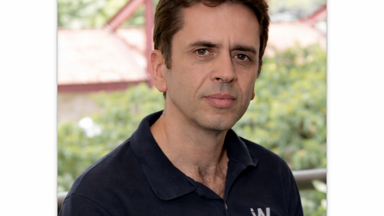 Headshot of Wagner Meira Jr., a professor of computer science, wearing a dark polo shirt, standing in front of a blurred outdoor background