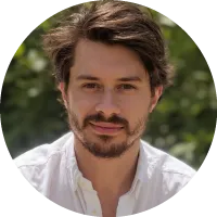 Headshot of Andrej Risteski with short hair and facial hair, wearing a light shirt, photographed outdoors.
