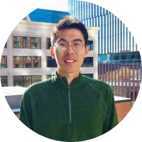 Headshot of Jie Ding wearing glasses and a green sweater, smiling outdoors.