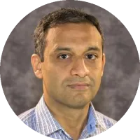 Headshot of Rizwan Ahmad wearing a collared shirt, smiling slightly against a neutral background.